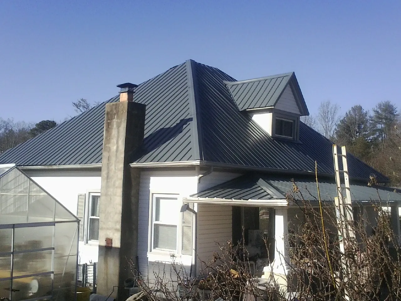 Dark blue standing seam metal roof on a white farmhouse with dormer — Slate & Tile Roof Repair by Roofing Brothers in South Pomfret