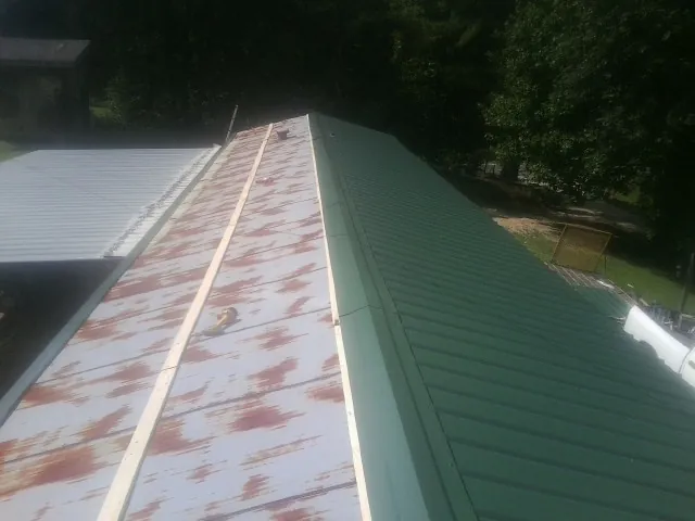 Old rusted panels beside newly installed green metal roofing — Wind Damage Roof Repair by Roofing Brothers in South Pomfret