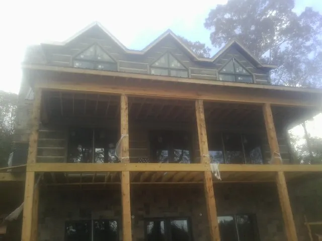Dormers and porch framing on a large log home under construction — Roof Coating work by our crew in South Pomfret