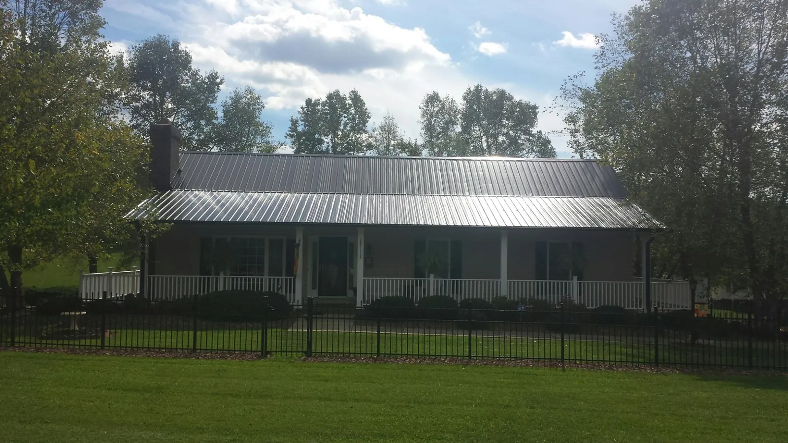 Gray metal roof on a brick ranch with a full width front porch — Gutter Guard Installation work by our crew in South Pomfret