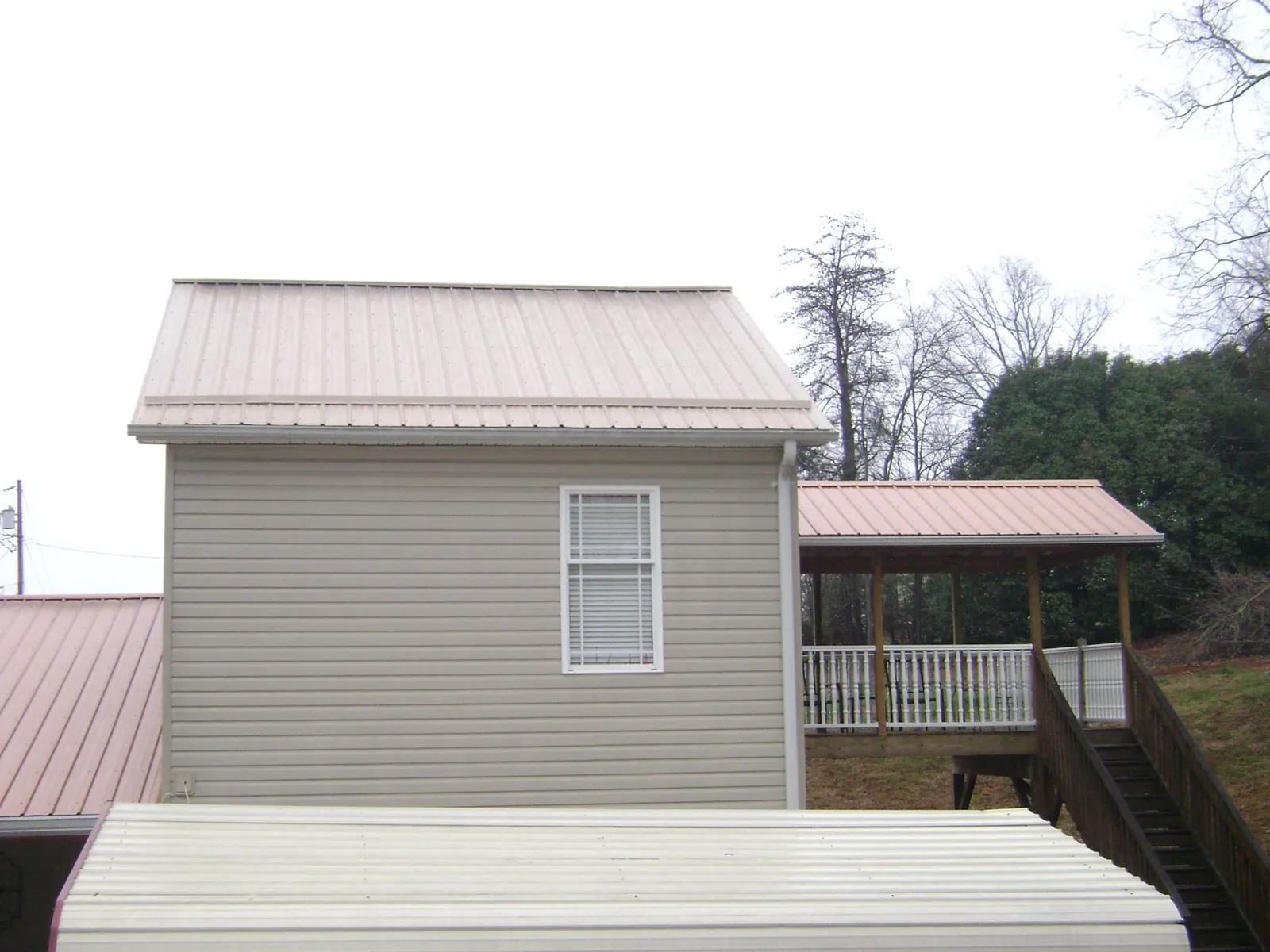 Tan metal roofs on a two story addition and attached porch, from a Roof Replacement job in South Pomfret