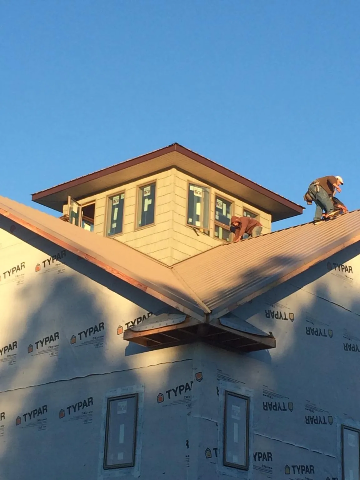 Roofers working around a rooftop cupola on a new metal roof at sunset — Roof Waterproofing in South Pomfret by Roofing Brothers